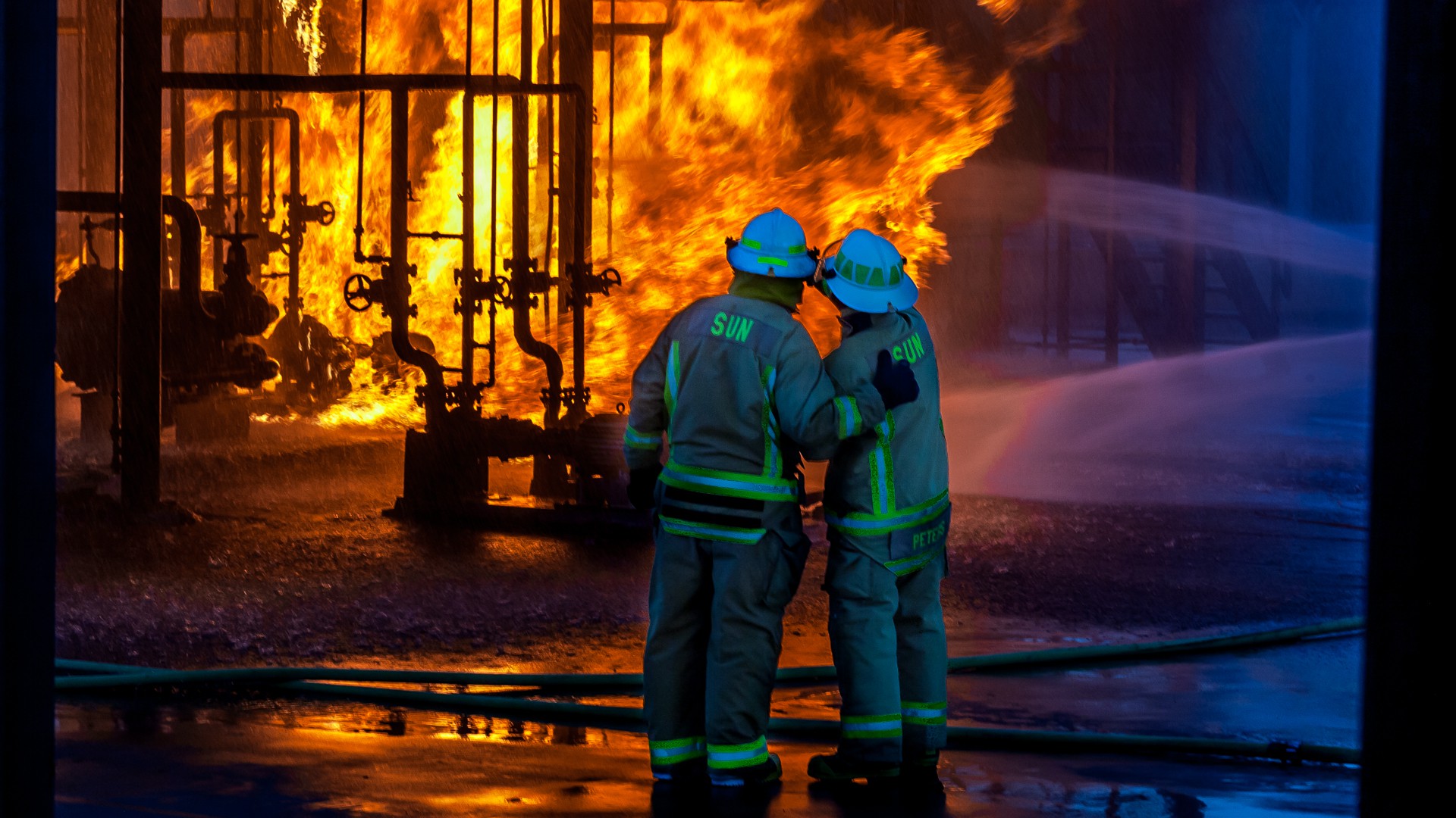 Two fire fighters watching an industrial fire